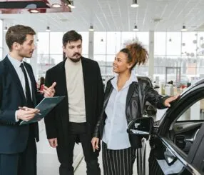 Vendedor apresenta carro para casal em concessionária