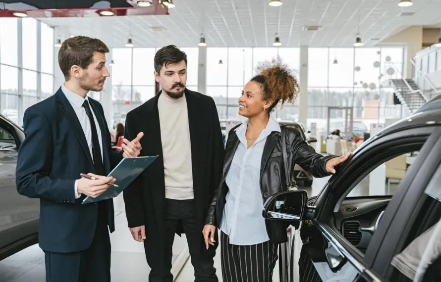 Vendedor apresenta carro para casal em concessionária
