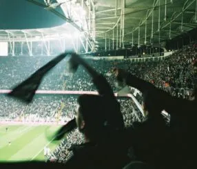 Torcedores segurando bandeiras e torcendo em um estádio lotado