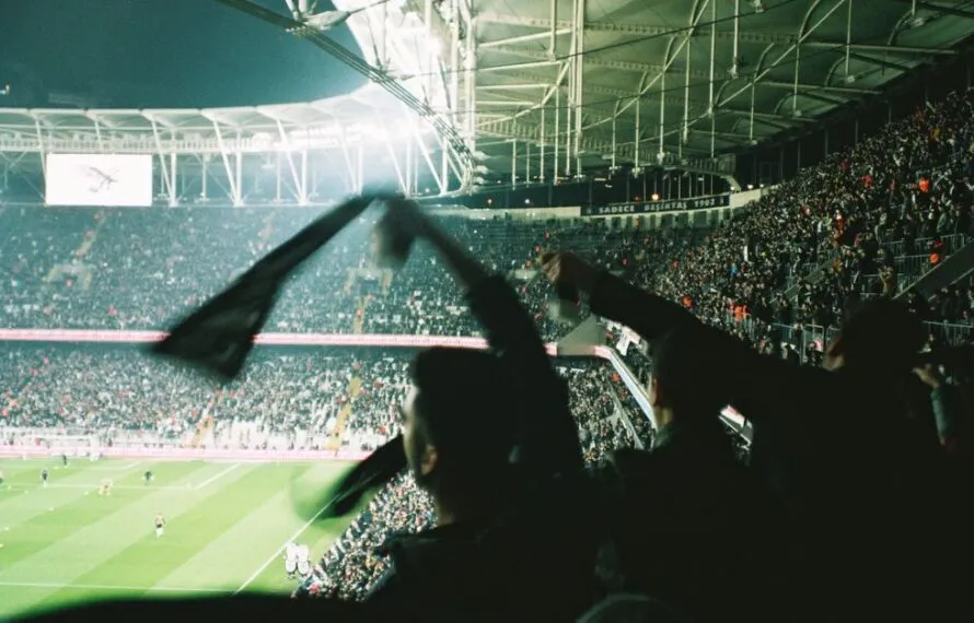 Torcedores segurando bandeiras e torcendo em um estádio lotado